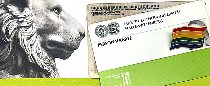 Symbolic image: Name change at MLU
[Image description: On the left half of the image you can see the head of the lion of the Löwengebäude. In his direction of view, an identity card and a personal card of MLU are lying in the right half of the picture. The ID card photo is obscured by a rainbow pin].